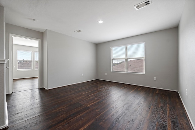 unfurnished room with baseboards, visible vents, and dark wood-style flooring