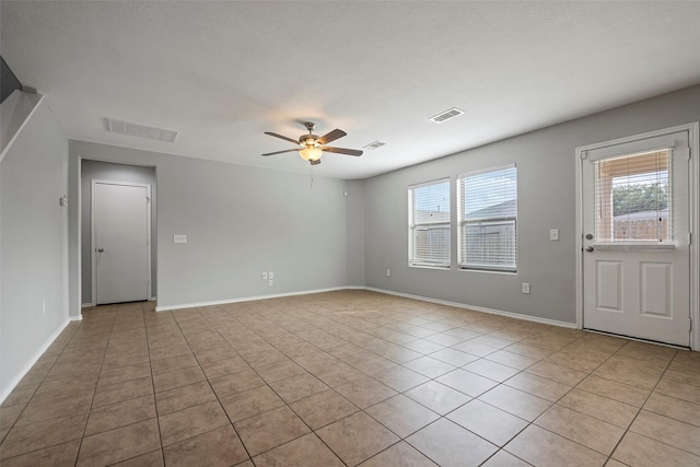 empty room with ceiling fan and light tile patterned floors