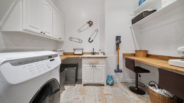 laundry area with cabinets, washer and dryer, and sink