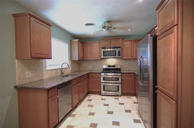 kitchen featuring ceiling fan, sink, backsplash, dark stone counters, and appliances with stainless steel finishes