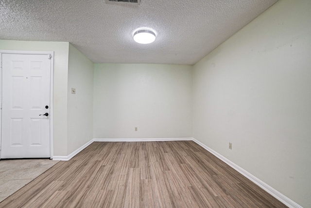 empty room featuring a textured ceiling and light wood-type flooring