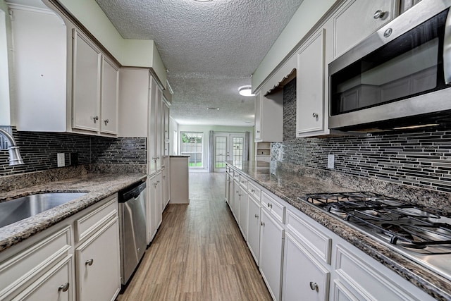 kitchen with backsplash, a textured ceiling, light hardwood / wood-style floors, french doors, and stainless steel appliances