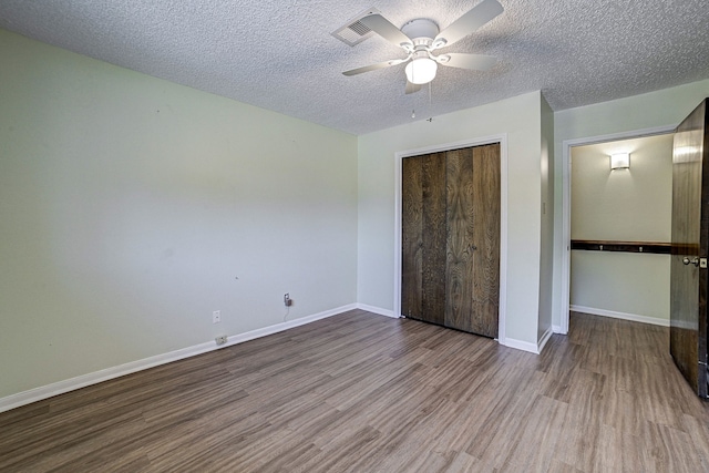 unfurnished bedroom featuring light hardwood / wood-style flooring, a textured ceiling, a closet, and ceiling fan