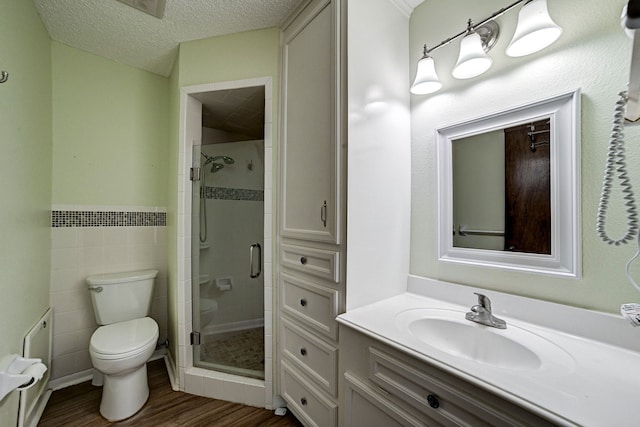 bathroom with a shower with door, a textured ceiling, wood-type flooring, toilet, and vanity