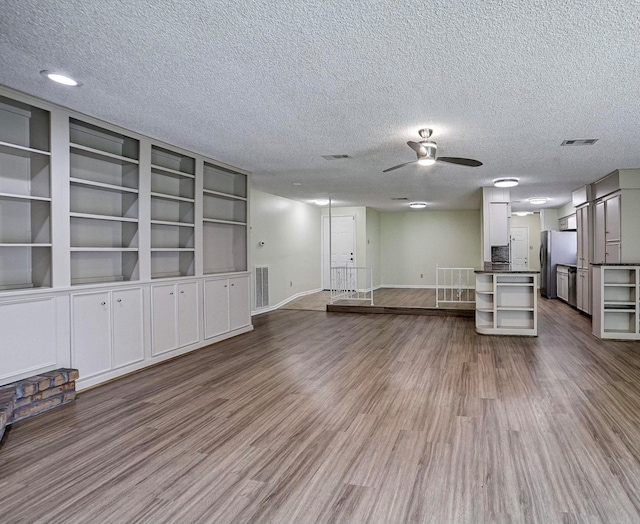 unfurnished living room featuring a textured ceiling, wood-type flooring, and ceiling fan