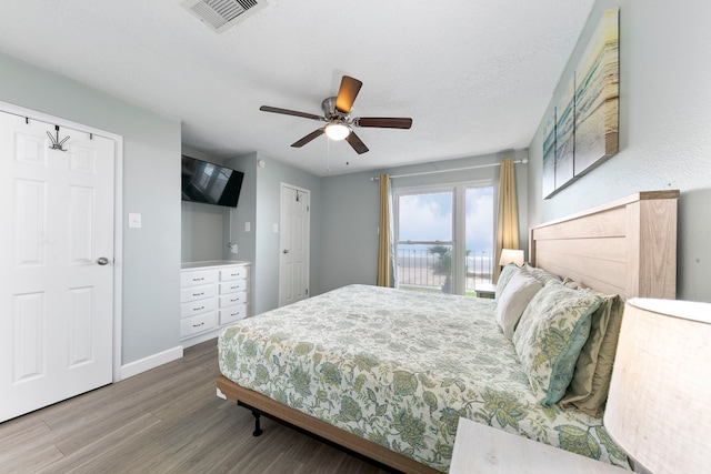 bedroom with ceiling fan, hardwood / wood-style flooring, and a textured ceiling