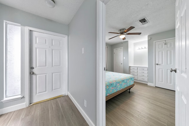 bedroom with a textured ceiling, hardwood / wood-style flooring, and ceiling fan