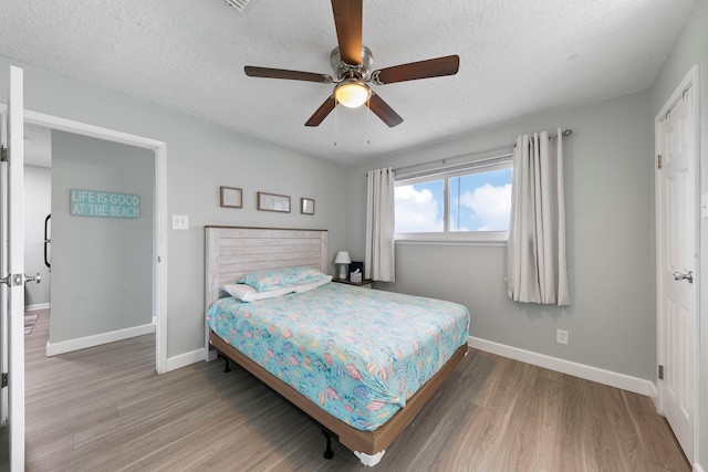 bedroom with ceiling fan, hardwood / wood-style flooring, and a textured ceiling