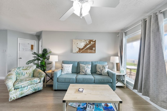 living room with a textured ceiling, wood-type flooring, and ceiling fan