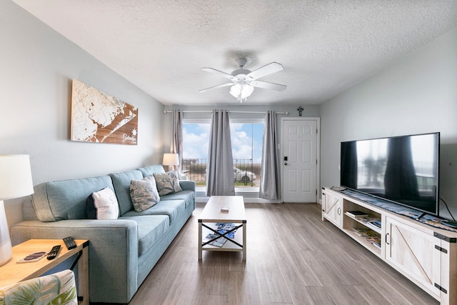 living room with a textured ceiling, hardwood / wood-style flooring, and ceiling fan