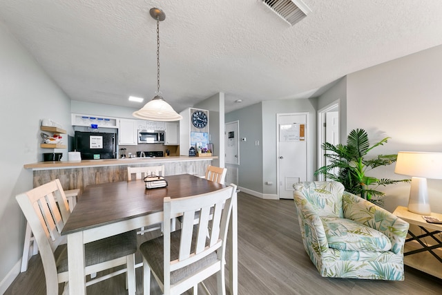 dining room with hardwood / wood-style floors and a textured ceiling