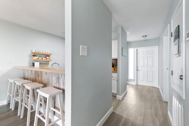 corridor with a textured ceiling and light hardwood / wood-style flooring