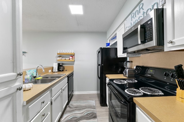 kitchen with black appliances, sink, light wood-type flooring, a textured ceiling, and white cabinets