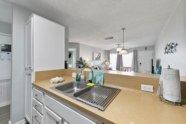 kitchen with sink, a textured ceiling, white cabinetry, ceiling fan, and hardwood / wood-style flooring