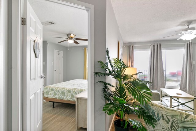 bedroom with light hardwood / wood-style flooring, a textured ceiling, and ceiling fan