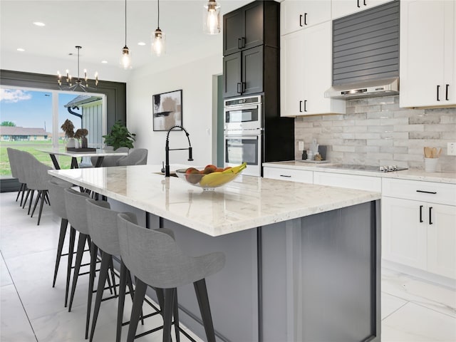 kitchen featuring white cabinetry, tasteful backsplash, an island with sink, and black electric cooktop