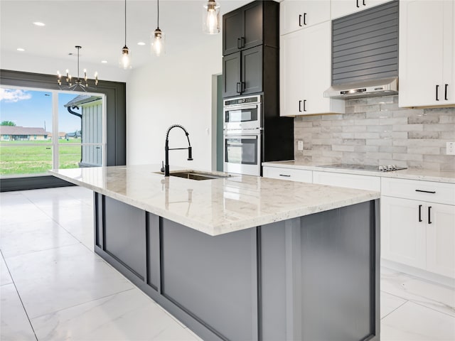 kitchen featuring light stone countertops, sink, white cabinetry, pendant lighting, and a kitchen island with sink