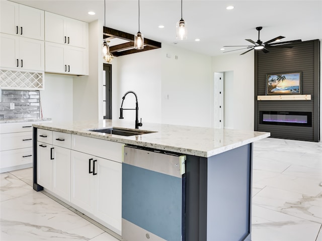 kitchen featuring white cabinets, a large fireplace, a center island with sink, dishwasher, and sink