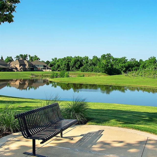 surrounding community with a yard, a patio, and a water view