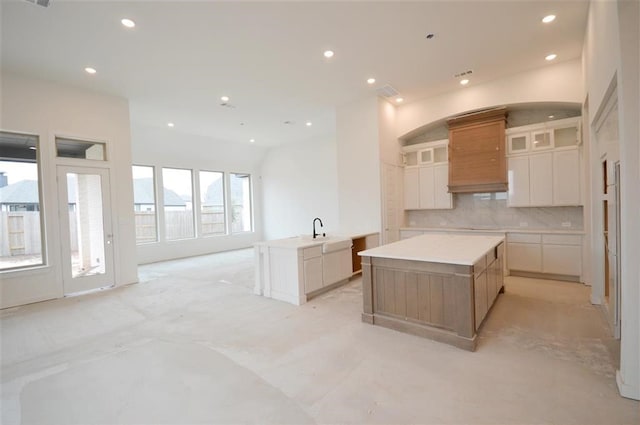 kitchen with a large island, sink, white cabinetry, and decorative backsplash