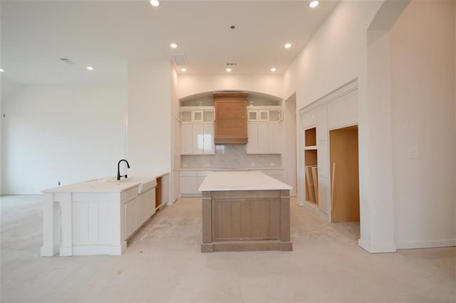 kitchen featuring white cabinetry, tasteful backsplash, a spacious island, and premium range hood