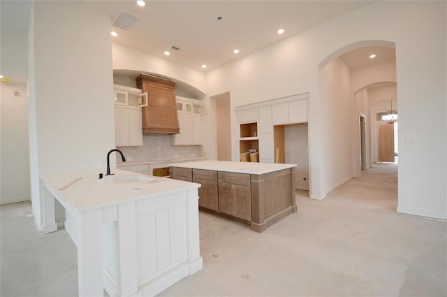 kitchen with a large island, sink, backsplash, custom range hood, and kitchen peninsula