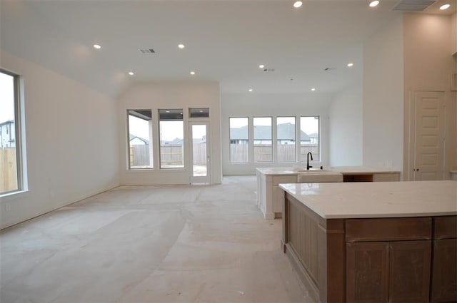 kitchen featuring light stone counters, a center island, and sink