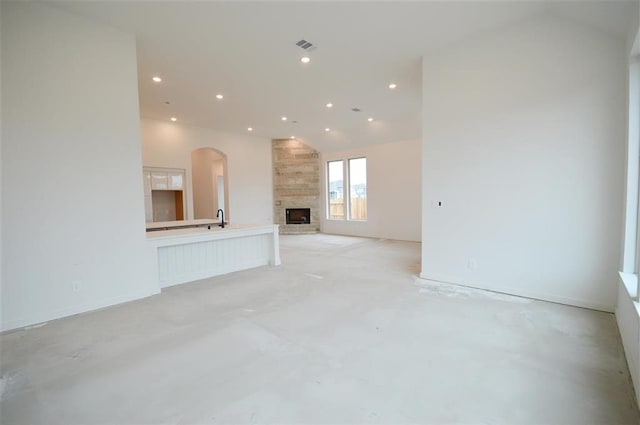 unfurnished living room with a large fireplace and high vaulted ceiling