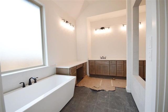 bathroom featuring vaulted ceiling, vanity, and a bathtub