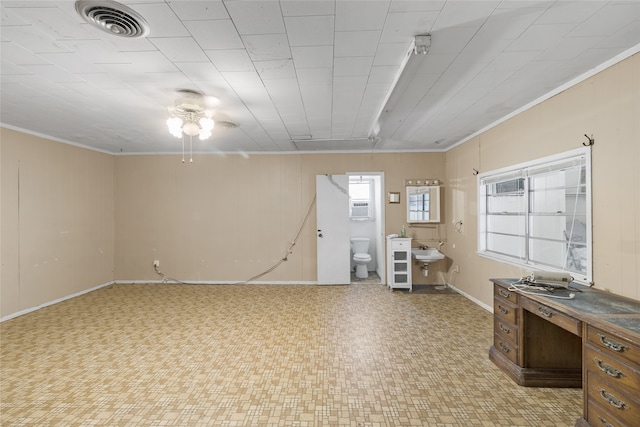 basement featuring a wall mounted air conditioner, ceiling fan, ornamental molding, and sink