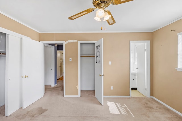 unfurnished bedroom featuring two closets, crown molding, ceiling fan, connected bathroom, and light colored carpet