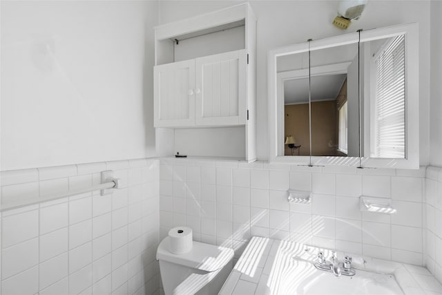 bathroom with sink, toilet, and tile walls