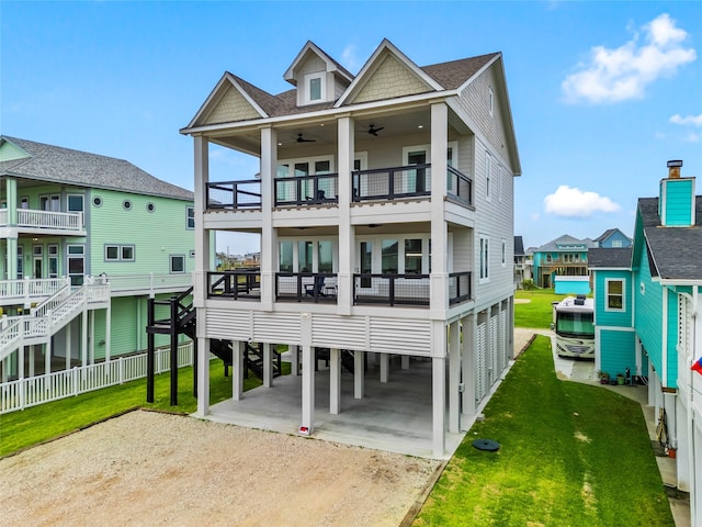 rear view of house featuring ceiling fan, a carport, a balcony, and a yard