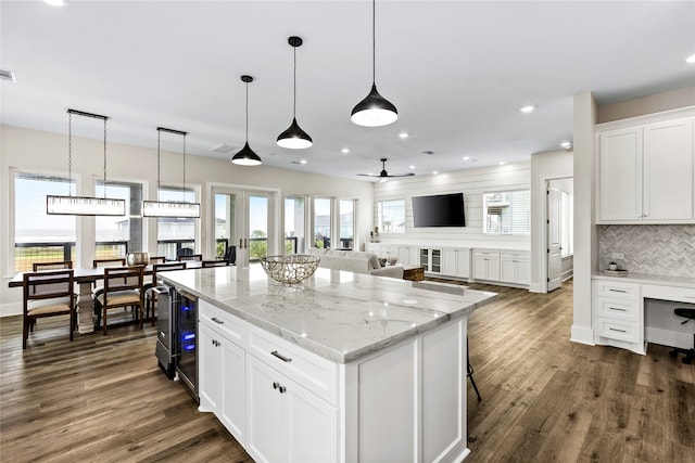 kitchen with dark hardwood / wood-style flooring, light stone counters, white cabinets, decorative backsplash, and decorative light fixtures