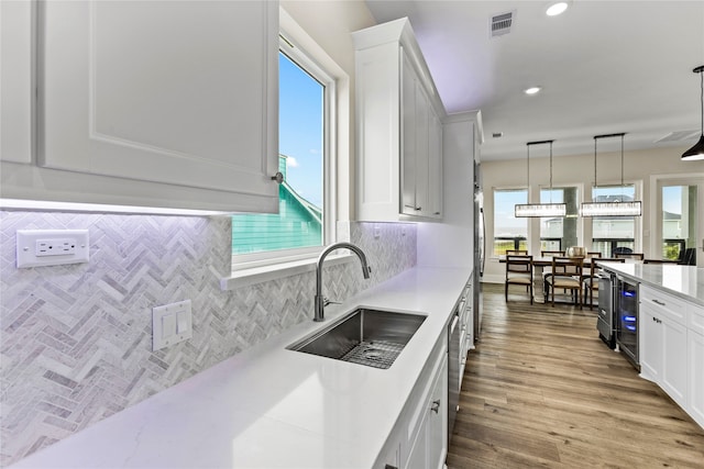 kitchen with light hardwood / wood-style floors, sink, tasteful backsplash, hanging light fixtures, and white cabinets