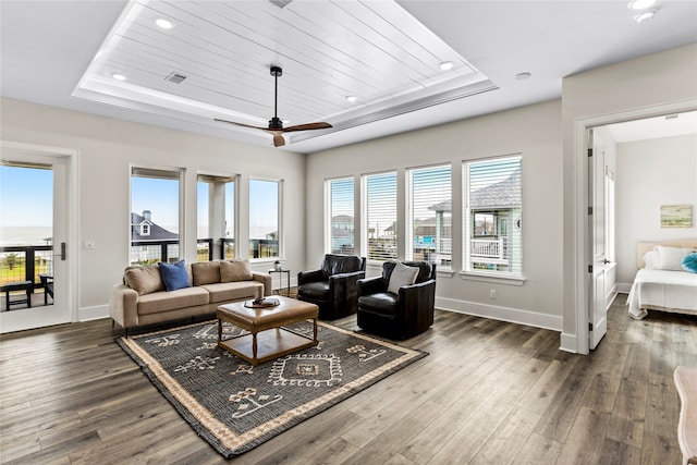 living room featuring ceiling fan, plenty of natural light, a raised ceiling, and dark hardwood / wood-style flooring