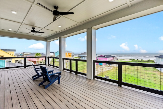 wooden terrace with ceiling fan, a yard, and a water view