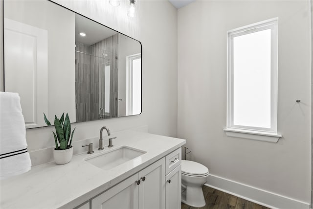 bathroom with toilet, vanity, hardwood / wood-style flooring, and a shower with door