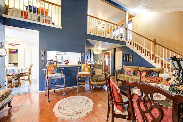 living room featuring ceiling fan, high vaulted ceiling, wood-type flooring, and a textured ceiling