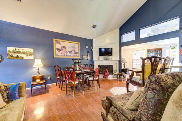 dining space featuring a notable chandelier, high vaulted ceiling, and light wood-type flooring