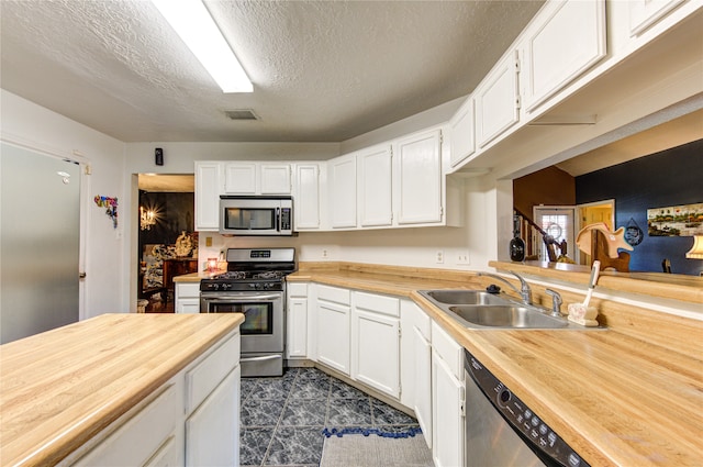 kitchen with white cabinetry, stainless steel appliances, a textured ceiling, and sink