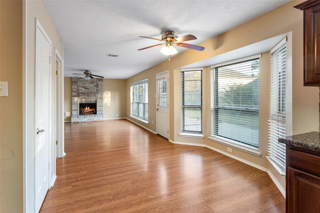 unfurnished living room featuring lofted ceiling, a textured ceiling, a fireplace, and light wood-type flooring