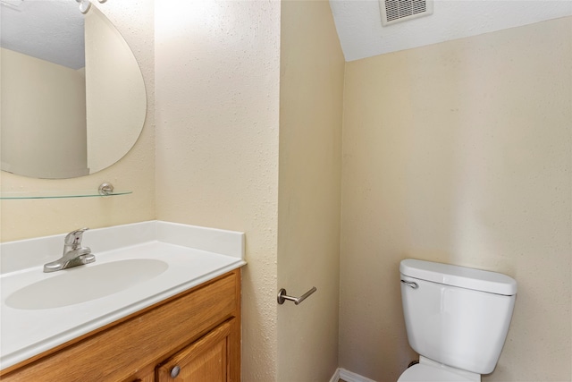 bathroom with toilet, a textured ceiling, and vanity