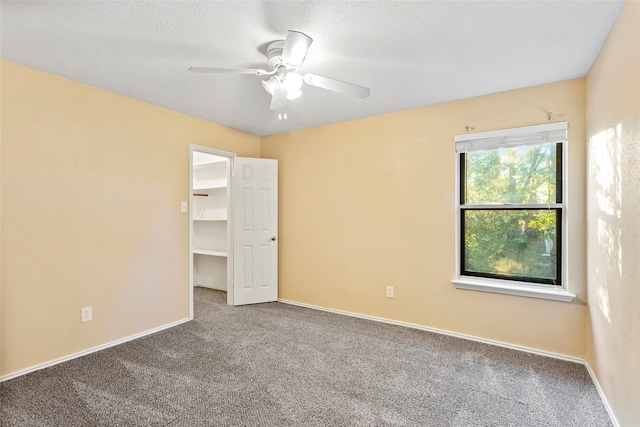 spare room featuring a textured ceiling, carpet, and ceiling fan