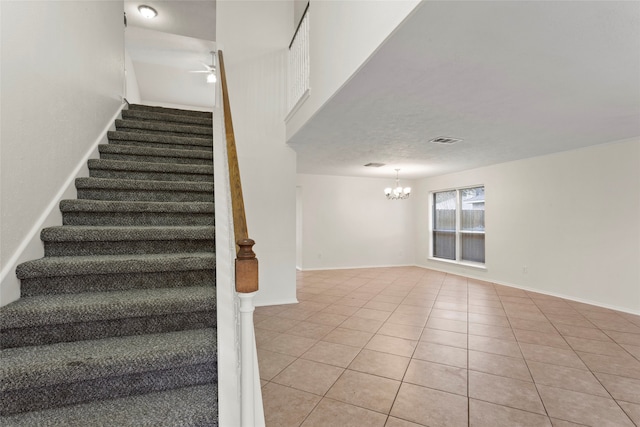 staircase with tile patterned flooring and ceiling fan with notable chandelier