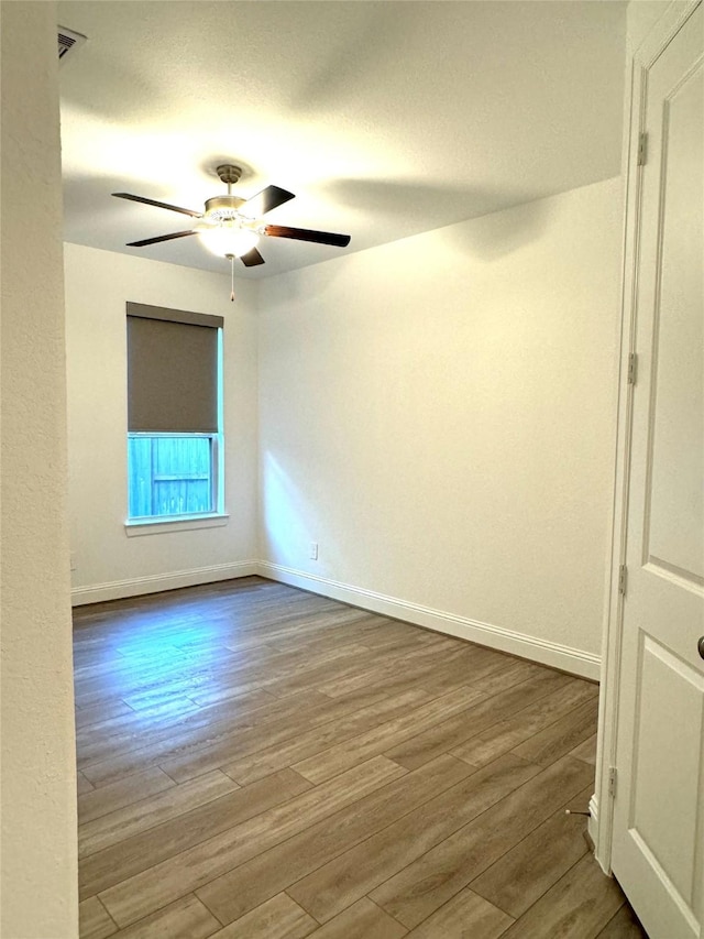 empty room with ceiling fan, wood finished floors, and baseboards