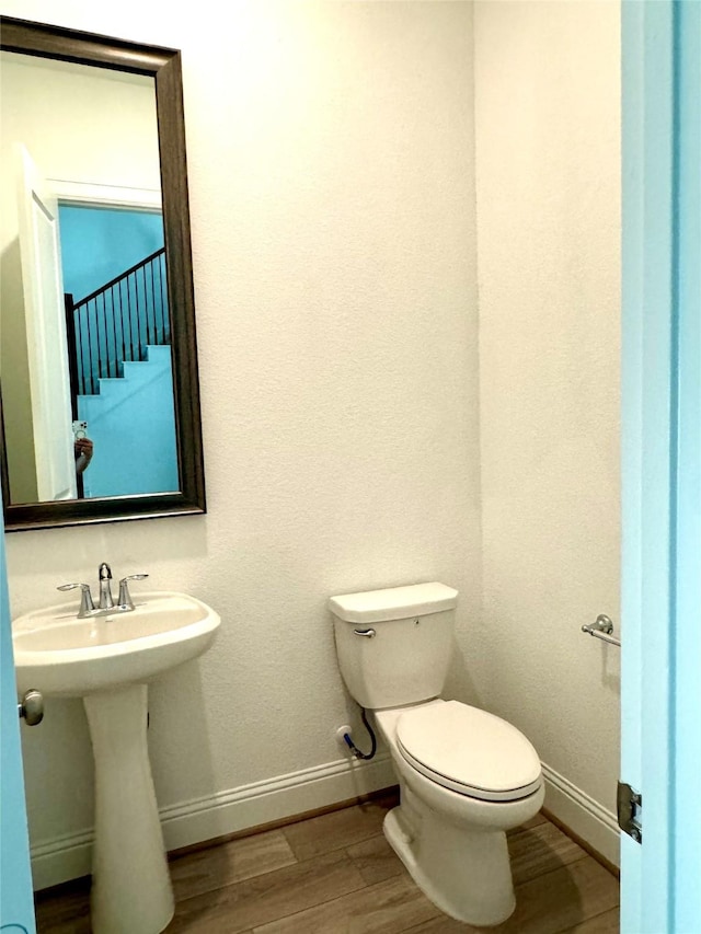 half bath with wood finished floors, toilet, and baseboards