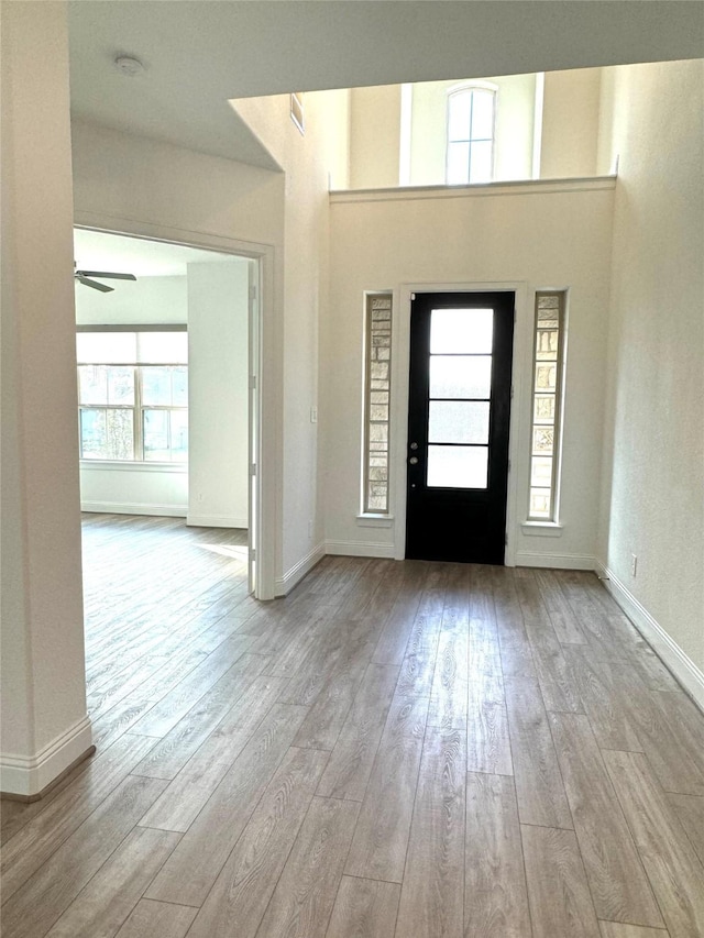 foyer entrance featuring baseboards, a ceiling fan, and light wood-style floors