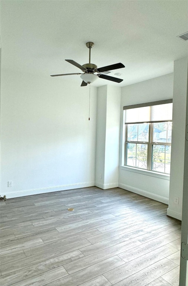 empty room with light wood-type flooring, baseboards, visible vents, and a ceiling fan