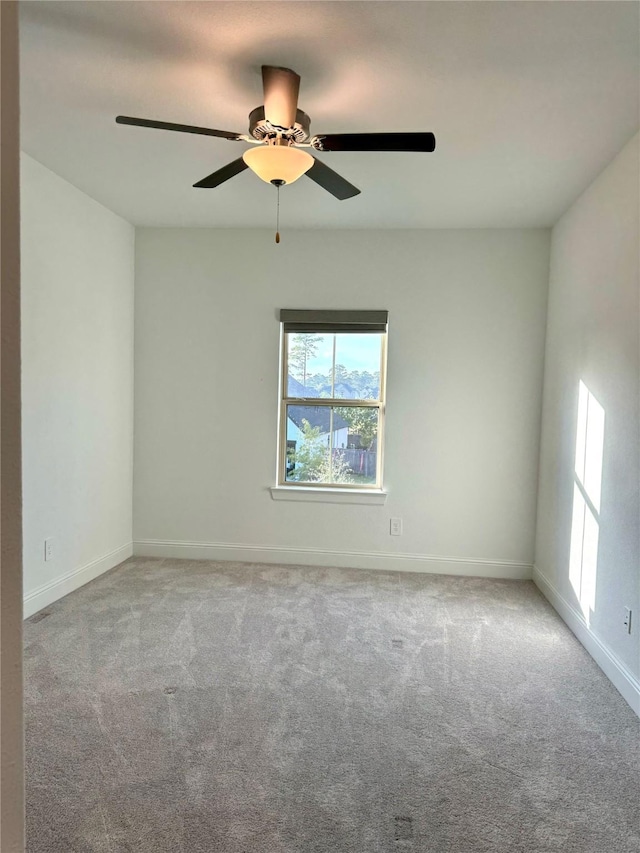 empty room featuring light colored carpet, ceiling fan, and baseboards